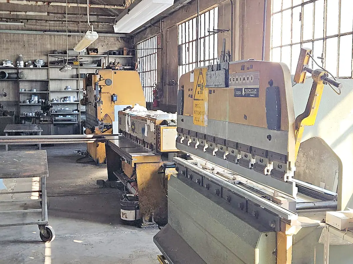 Pressa piegatrice e scaffali di raccordi nell’officina IMPES, dove realizziamo le condotte